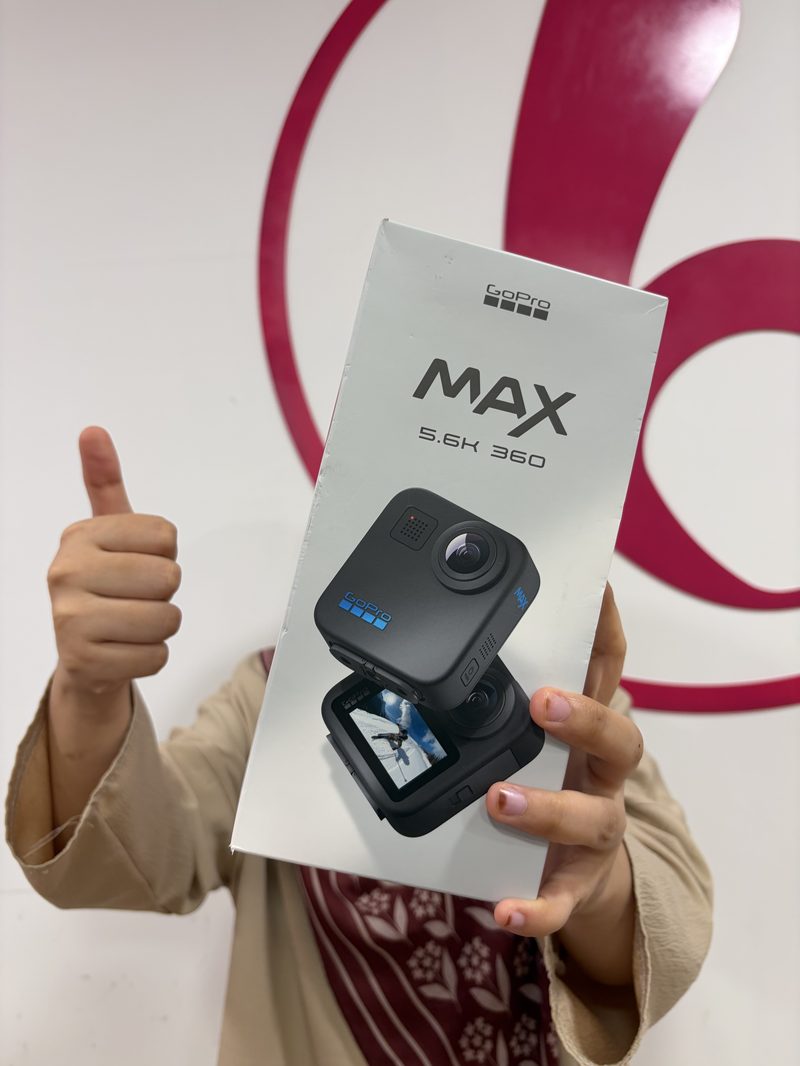 Happy Berry Nice customer holding a GoPro MAX 360 camera box in front of the brand wall after a sale